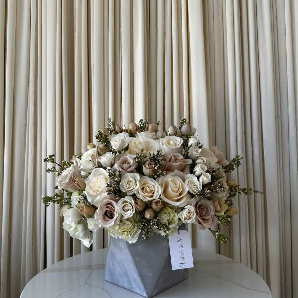 Cream and blush rose arrangement in a gray geometric vase