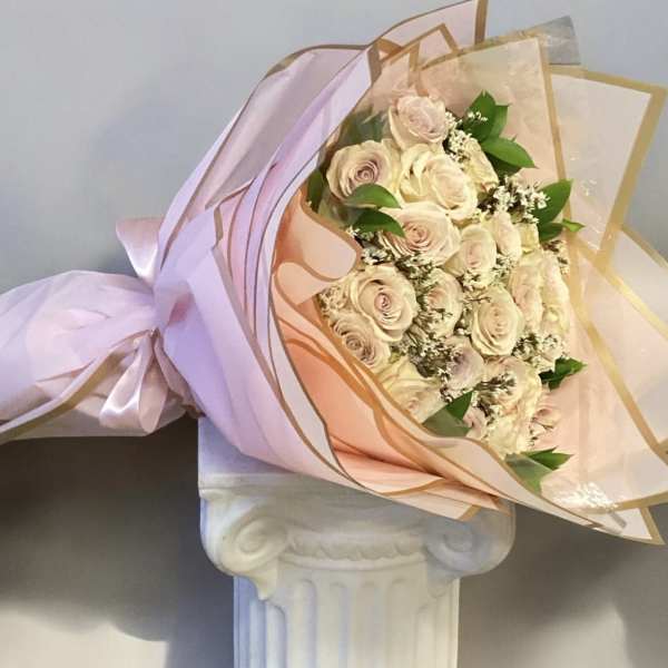 Bouquet of pale pink roses wrapped in pink and gold paper