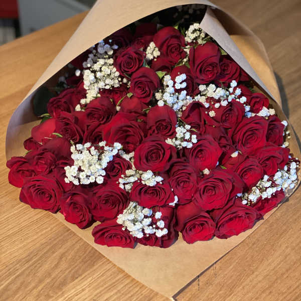 Bouquet of red roses with white baby's breath in brown paper