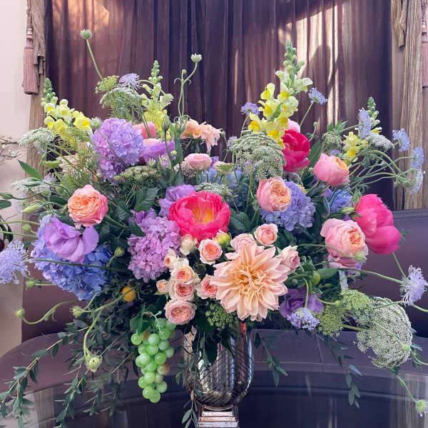 Large mixed bouquet in a metallic vase with pink, purple, and yellow blooms