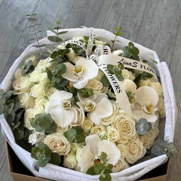 Cream roses and white orchids in a wrapped bouquet box
