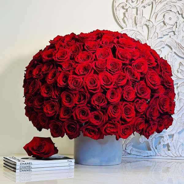 Large bouquet of red roses in a gray vase with a single rose beside it