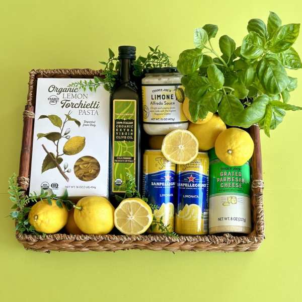 Gift basket with lemons, basil, pasta, sauce, olive oil, and sparkling drinks