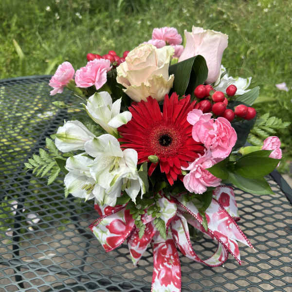 Bouquet of pink, white, and red flowers tied with a floral ribbon.