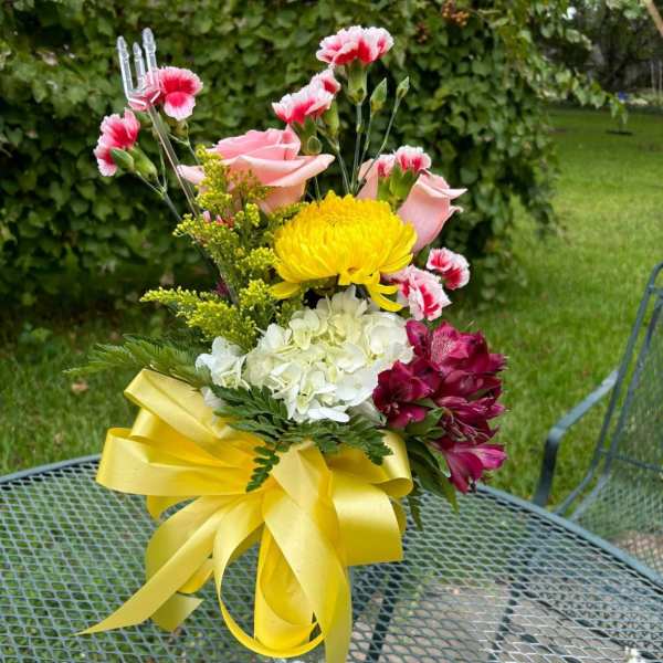 Bouquet of pink roses, yellow chrysanthemum, white hydrangea, and magenta alstroemeria in a glass vase