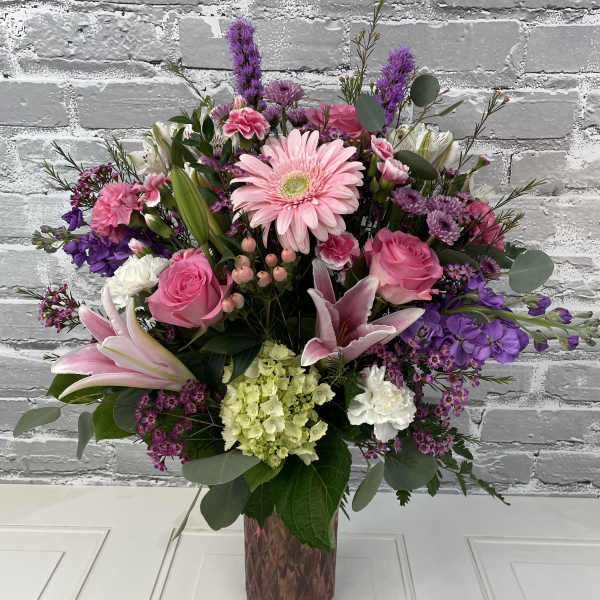 Pink and purple mixed flower arrangement in a glass vase