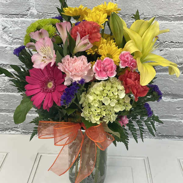 Colorful mixed bouquet in a glass vase with an orange ribbon