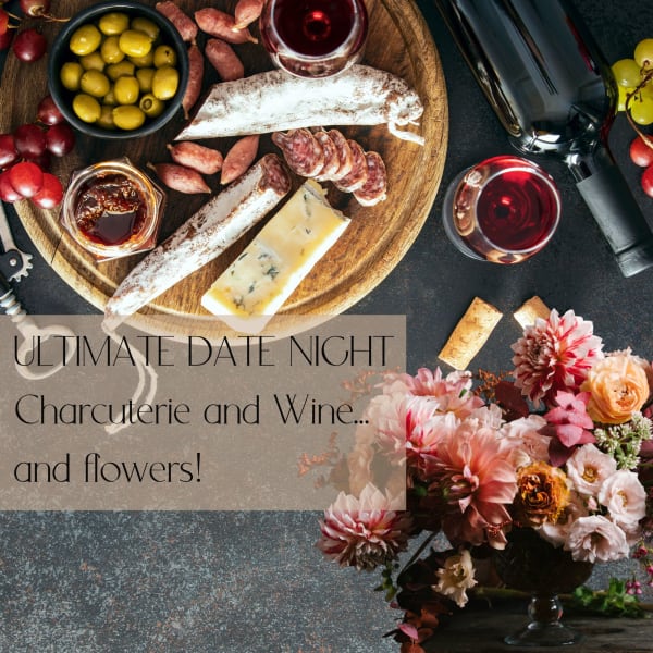 Charcuterie board with wine glasses and a floral arrangement