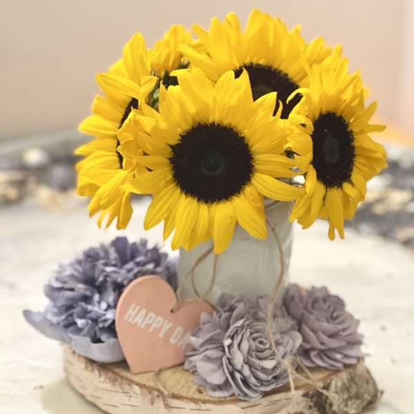 Sunflowers in a birch bark container with lavender flowers and a heart tag