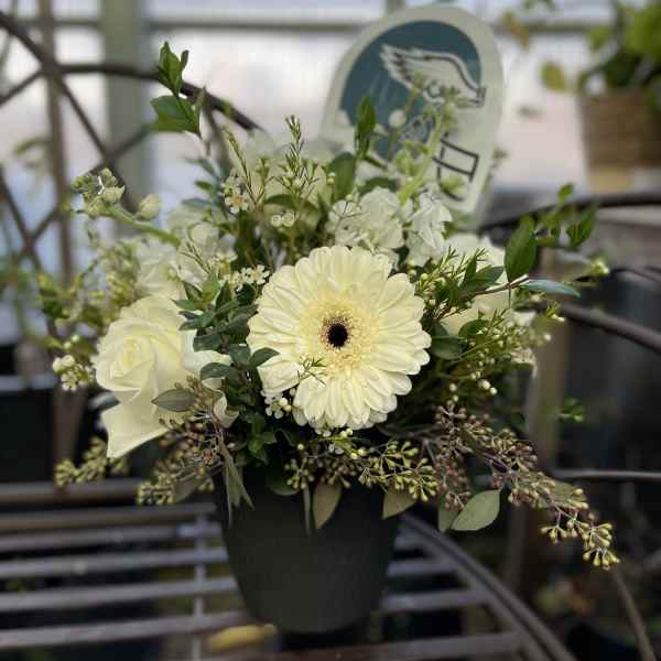 White flowers arranged in a black pot with greenery