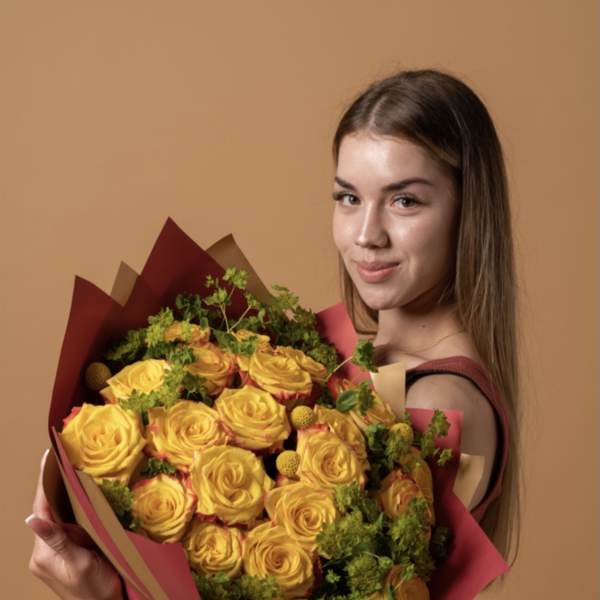 Woman holding a bouquet of yellow roses wrapped in burgundy paper