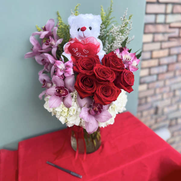 Bouquet of red roses and pink orchids with a teddy bear topper