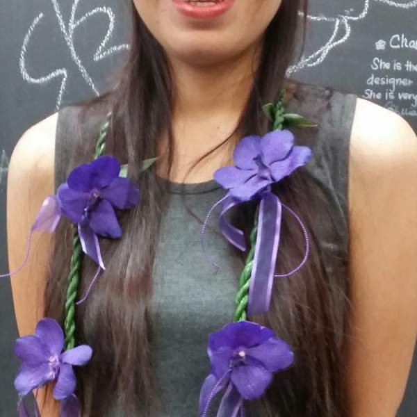 Woman wearing a purple flower lei with ribbon accents
