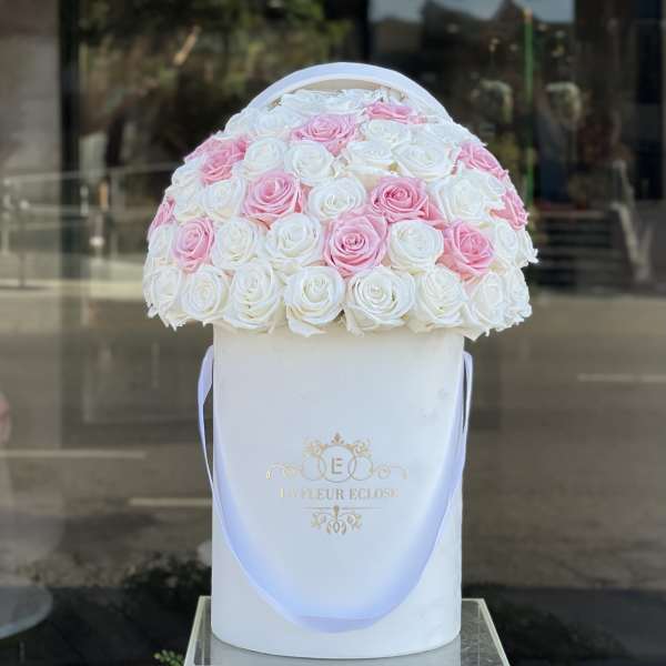 Pink and white roses arranged in a round white hat box