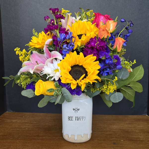 Colorful bouquet with sunflowers, roses, lilies, and a white vase