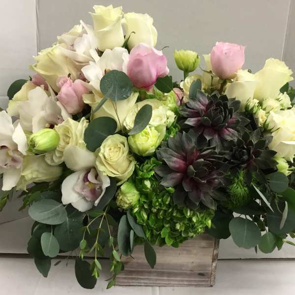 Mixed bouquet of white and pink roses with dark succulents in a wooden box