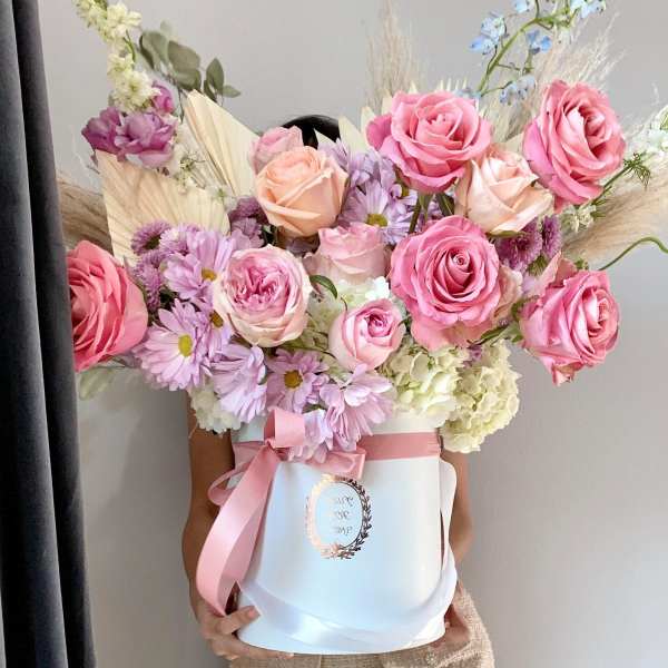 Large bouquet of pink roses and lavender daisies in a white hat box