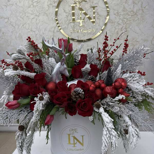 Red roses and tulips arranged with frosted branches in a white box