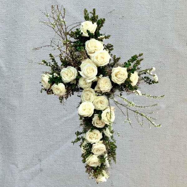 White rose cross arrangement with greenery on a textured background