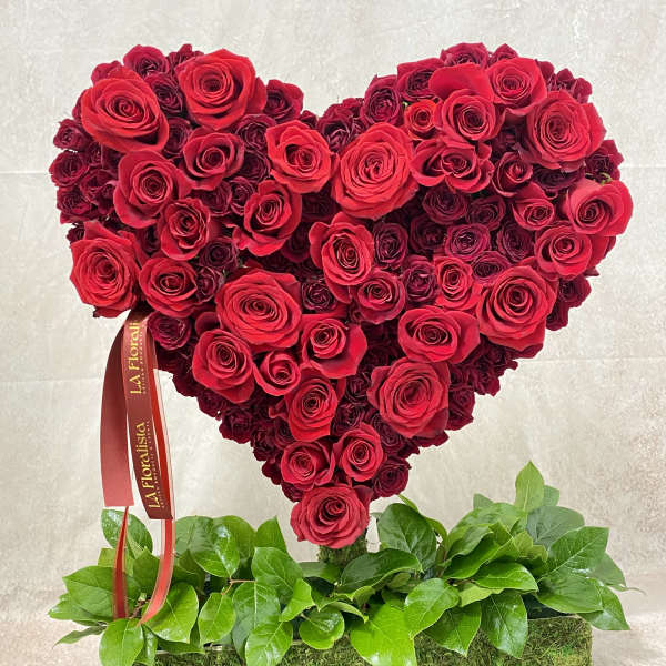 Heart-shaped red rose arrangement on a moss-covered base