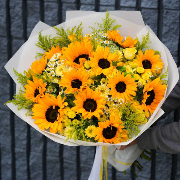 Bouquet of orange sunflowers and yellow flowers wrapped in white paper