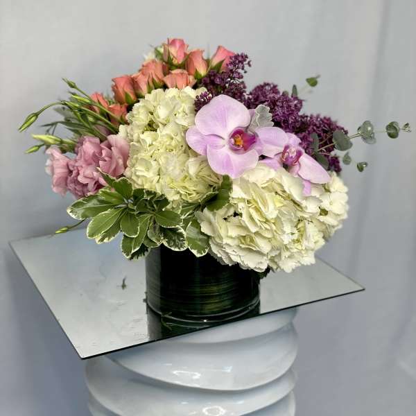 Pink roses, white hydrangeas, and lavender orchids in a black vase
