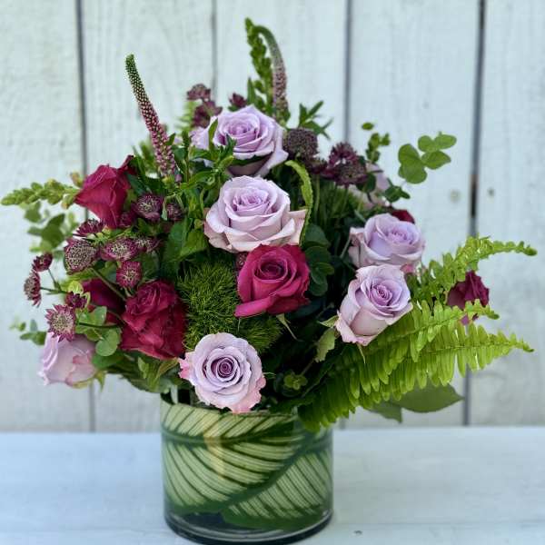 Pink and lavender roses arranged in a glass vase