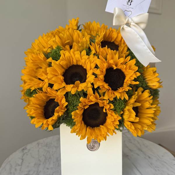 Bouquet of bright yellow sunflowers in a white gift box with a ribbon