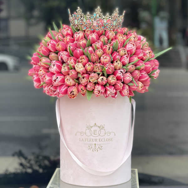 Pink tulip bouquet topped with a jeweled crown in a pale pink hatbox
