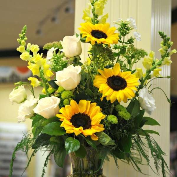 Sunflower and white rose arrangement in a clear glass vase