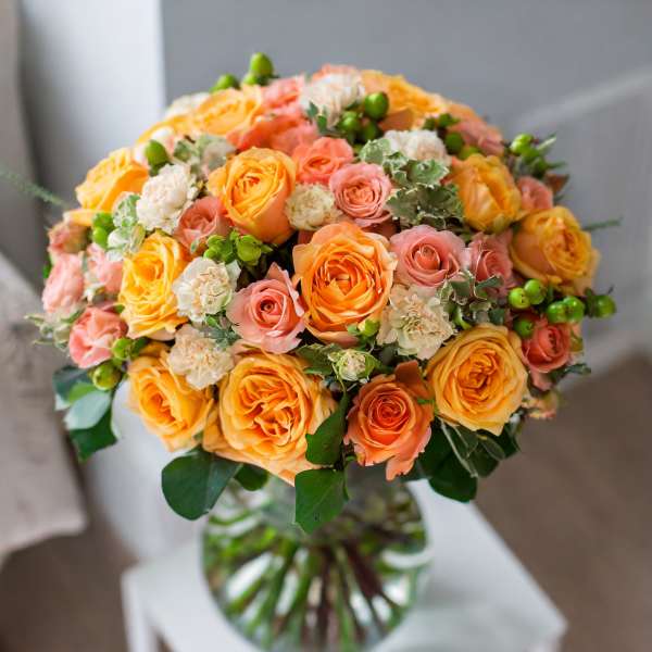 Bouquet of orange and pink roses in a glass vase