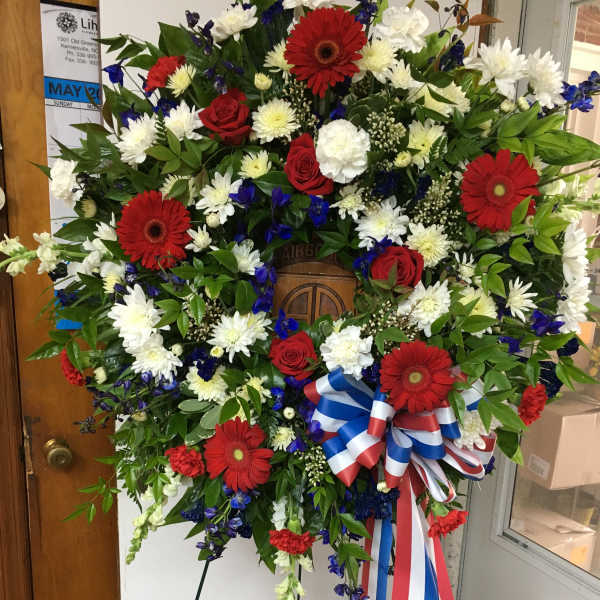 Large standing wreath of red, white, and blue flowers on an easel