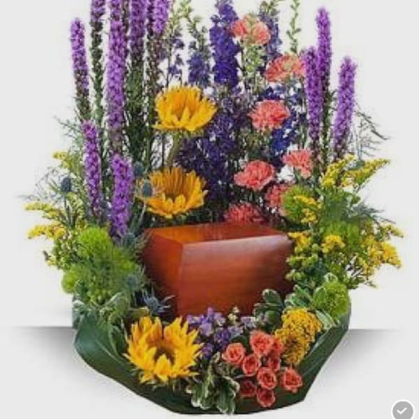 Tall mixed floral arrangement with purple spikes, yellow blooms, and coral flowers in a wooden container