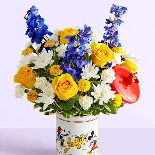 Bouquet of yellow roses, white daisies, and blue flowers in a Mickey Mouse tin