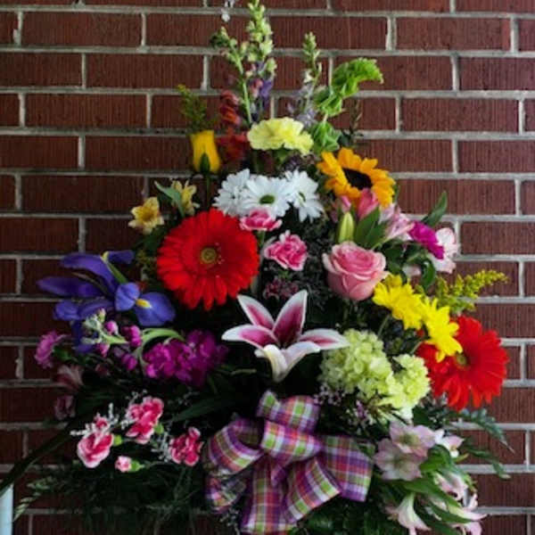 Colorful mixed flower arrangement in a glass vase with a plaid ribbon