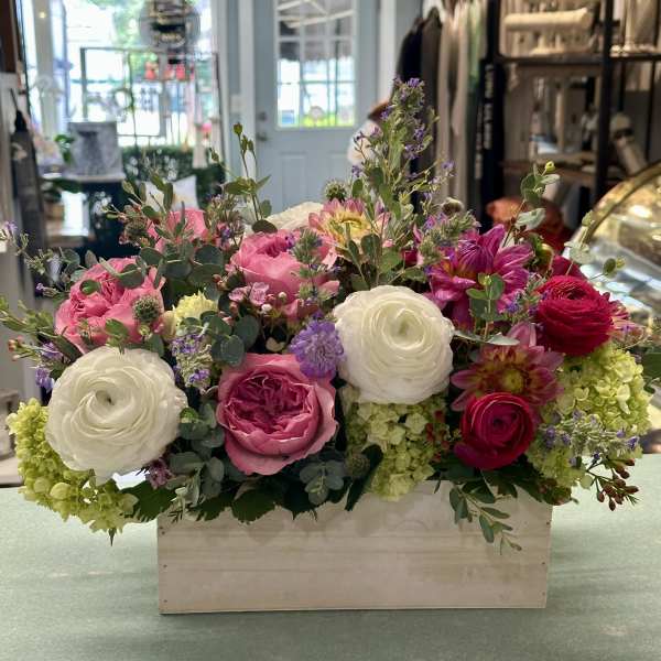 Mixed pink and white flowers arranged in a wooden box