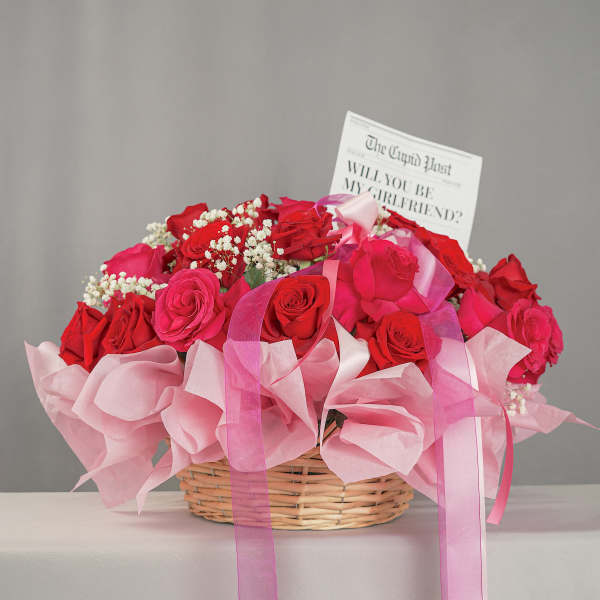 Basket of red and pink roses with a card and pink ribbon