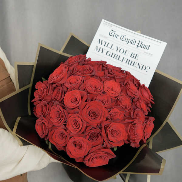 Bouquet of red roses wrapped in black paper with a printed card