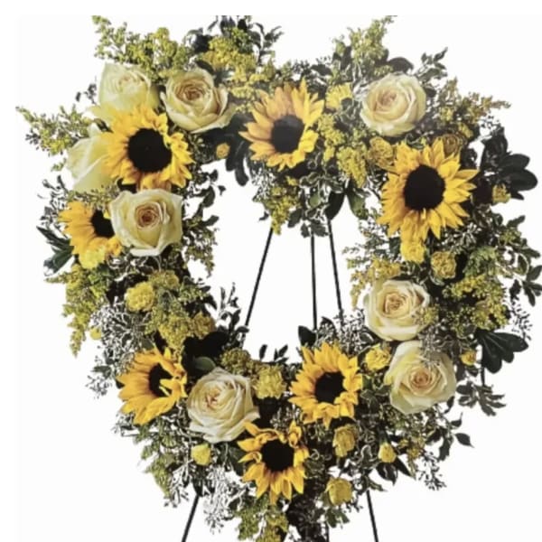 Heart-shaped standing wreath of yellow sunflowers and white roses on a metal easel