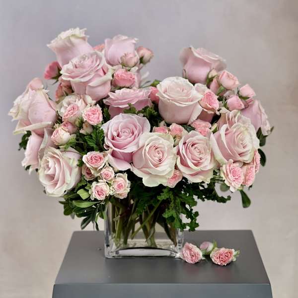 Pink roses and spray roses arranged in a clear glass vase