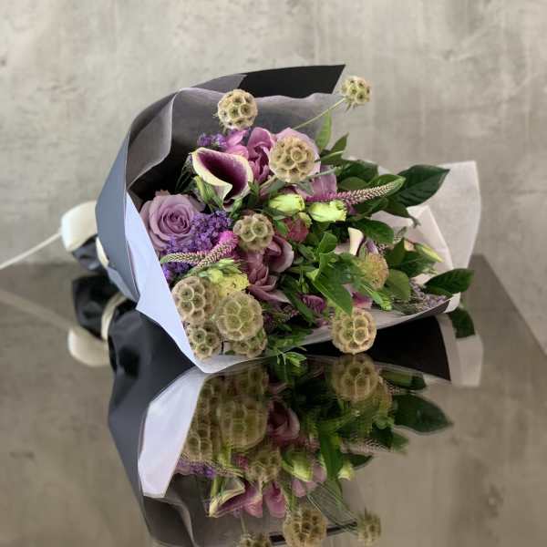 Bouquet of purple and pink flowers wrapped in black and white paper
