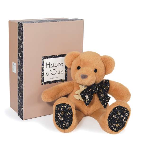 Plush teddy bear with a ribbon bow beside a pink gift box