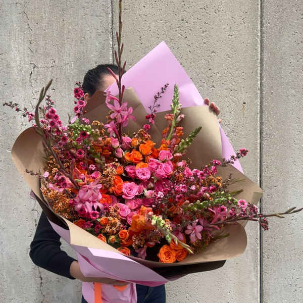 Large bouquet of pink and orange flowers wrapped in paper