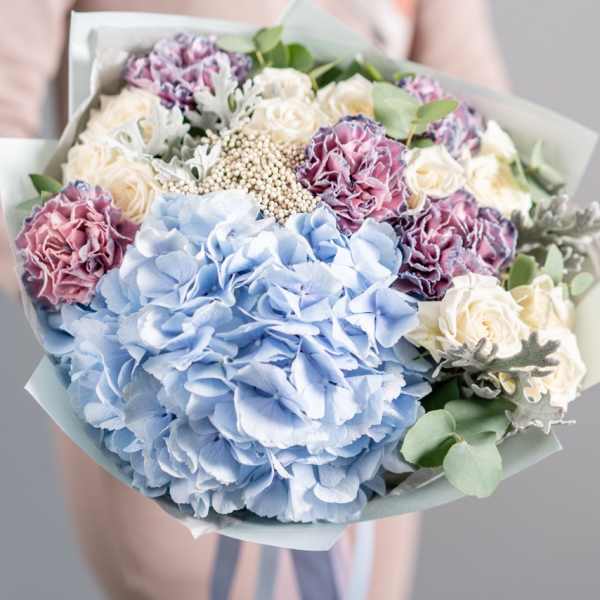 Bouquet of blue hydrangeas, cream roses, and purple carnations