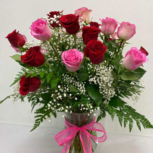 Bouquet of red and pink roses in a glass vase with a pink ribbon