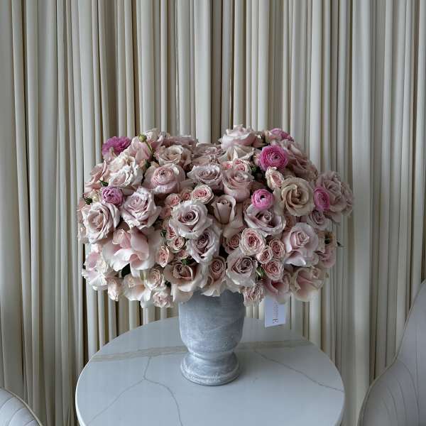 Large pink rose arrangement in a gray pedestal vase