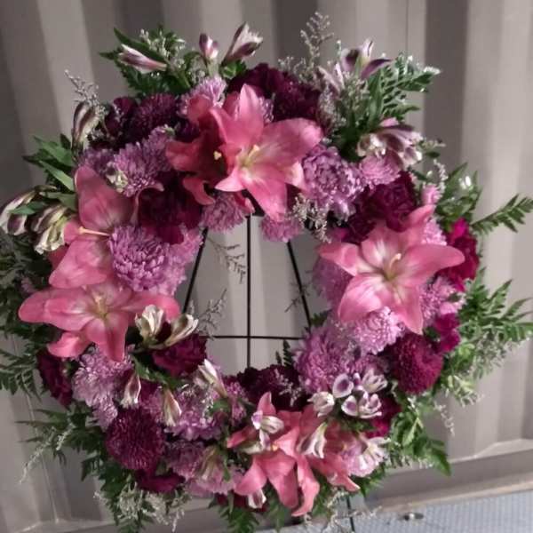 Pink and purple floral wreath on a black stand