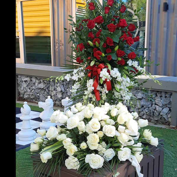 Tall floral display with red and white roses on a wooden stand