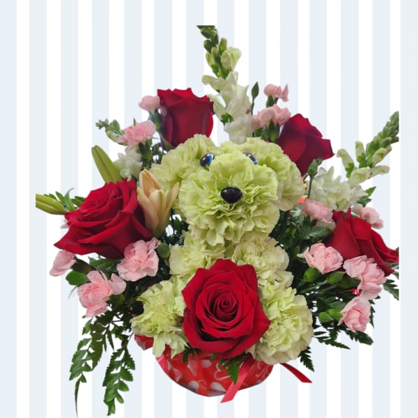 Bouquet of red roses, pale green carnations, and pink spray carnations in a heart-patterned wrap