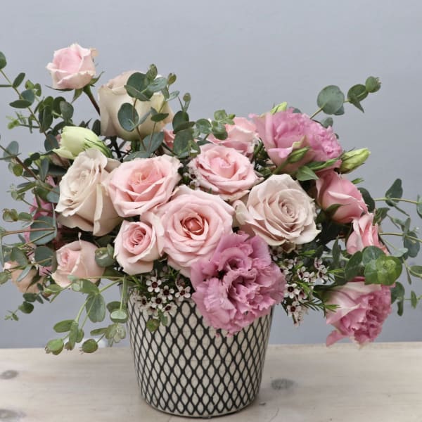 Pink and cream roses with greenery in a patterned vase
